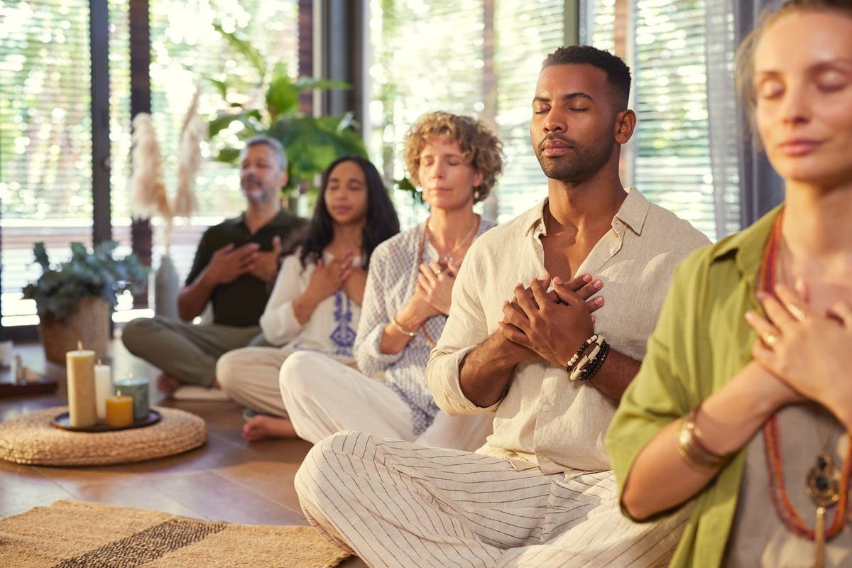 Grupo diverso meditando con las manos en el corazón